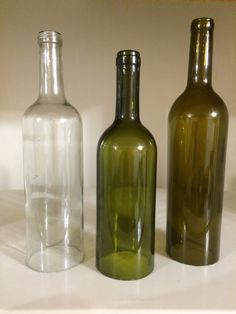 three empty glass bottles sitting on top of a white countertop next to each other