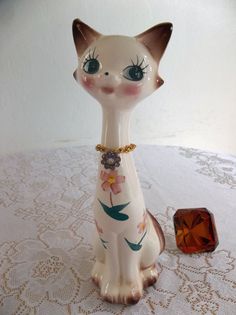 a white cat figurine sitting on top of a table next to a crystal cube