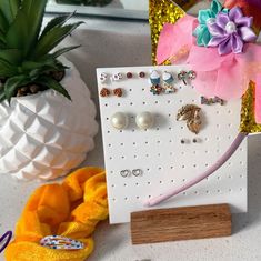 there is a pineapple next to some earrings on a card and a pineapple in the background