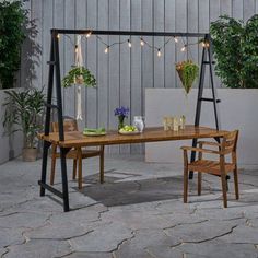 a wooden table with two chairs and some lights on it in front of a building