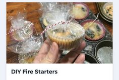 someone is holding up some cupcakes in plastic wrappers on a wooden table