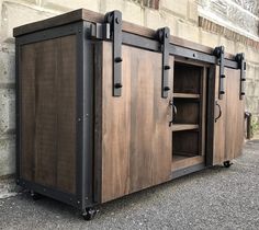 a large wooden cabinet sitting on top of a street next to a brick wall,