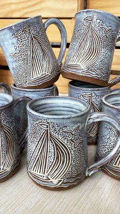 a group of coffee mugs sitting on top of a wooden table next to each other