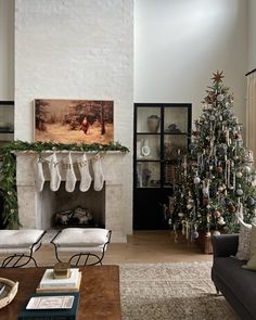 a living room decorated for christmas with stockings hanging from the mantel, fireplace and tree