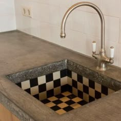 a kitchen sink with a checkerboard design under the faucet and countertop