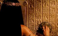 an egyptian woman is looking at the wall with her hand on it's face