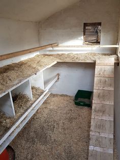 an empty barn with hay in the floor and shelves on the wall next to it