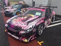 two cars parked next to each other in a parking lot with graffiti painted on them