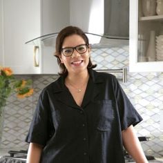 a woman standing in the kitchen with her hands on her hips and smiling at the camera