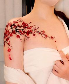 a woman with red flowers painted on her chest and arm, wearing a white dress