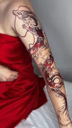 a woman in a red dress with tattoos on her arm