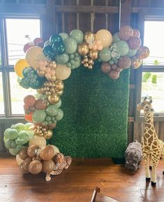 a giraffe is standing in front of a balloon arch