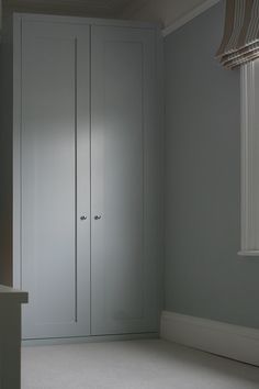 an empty room with two white closets in the corner and a window on the far wall