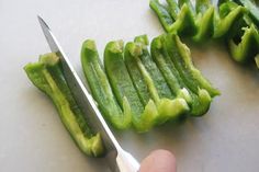 someone cutting up green peppers with a pair of scissors