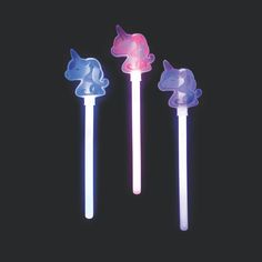 three different colored toothbrushes in the shape of unicorns on black background, one is pink and one is blue