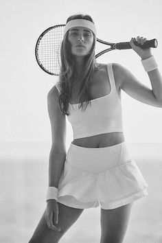 a woman holding a tennis racquet on top of a beach