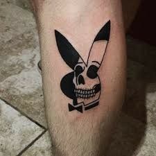 a man with a knife and skull tattoo on his leg