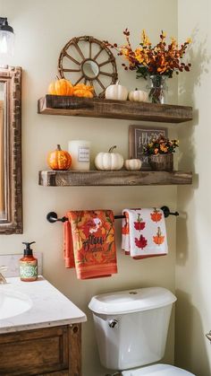 a bathroom decorated for fall with pumpkins, flowers and towels hanging on the wall