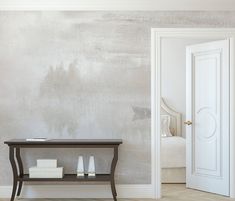 an empty room with a table and two white candles on the shelf next to it