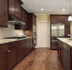 a large kitchen with wooden cabinets and stainless steel appliances, along with marble counter tops