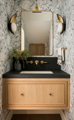 a bathroom sink sitting under a mirror next to a wall mounted faucet in front of a wooden cabinet