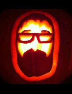 a pumpkin carved to look like a man with glasses and beard, in the shape of a face