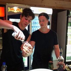 two young men are preparing drinks in a bar