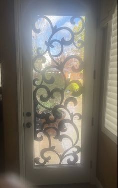 an open door with a decorative glass design on it's side and the sun shining through