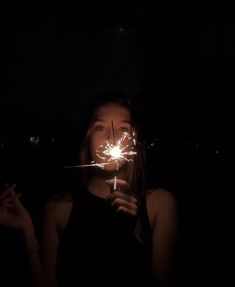 a woman holding a sparkler in the dark