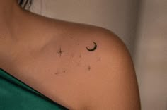 a woman's shoulder with a crescent and stars tattoo on it