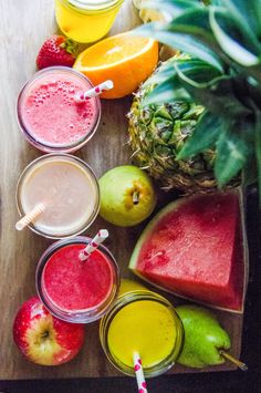 various fruits and juices on a table with strawberries, oranges, apples, watermelon, pineapple