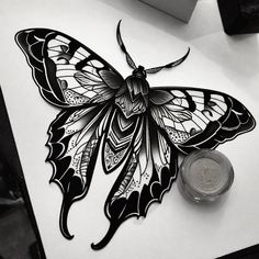 a black and white drawing of a butterfly sitting on top of a table next to a coin