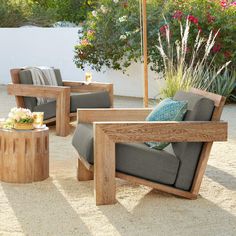 an outdoor seating area with two chairs and a coffee table in the middle, surrounded by flowers