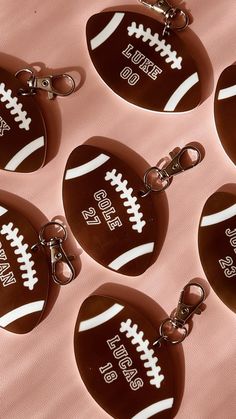 six chocolate football keychains are shown on a pink background