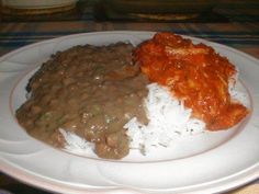 a white plate topped with rice covered in beans and sauce next to other food items