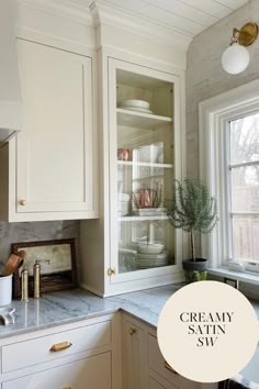 a kitchen with white cabinets and marble counter tops in front of a window that says creamy satin