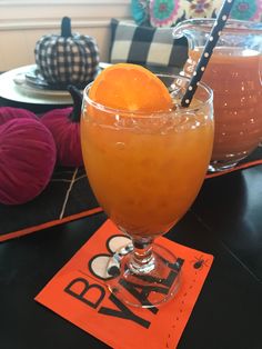 two glasses filled with drinks sitting on top of a table next to pumpkins and yarn