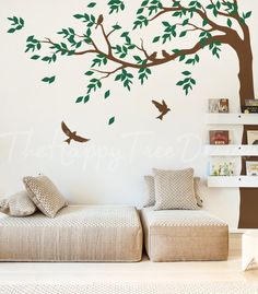 a tree with two birds on it is next to a couch and bookshelf