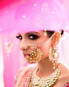 a woman in a pink outfit with jewelry on her head and nose ring, wearing an elaborate necklace