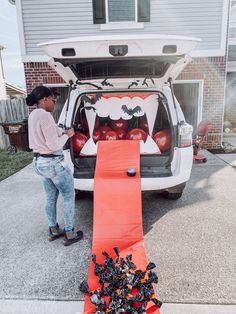 a man standing in front of a van with halloween decorations on it's trunk