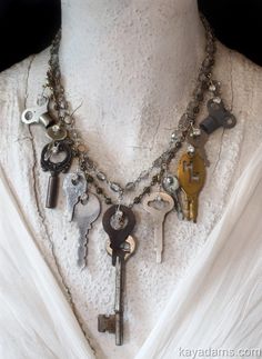 a necklace with several keys attached to it on a mannequin neckline in front of a white shirt