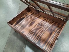 an empty wooden box sitting on top of a cement floor next to a metal frame