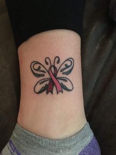 a woman's foot with a pink ribbon tattoo on her left side ribcage