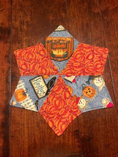 an orange and blue patchwork quilt on a wooden floor with pumpkins in the center