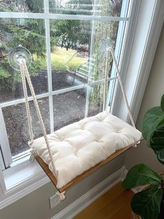 a window with a swing hanging from it's side next to a potted plant