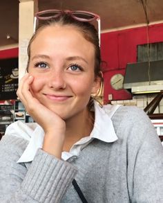 a woman is smiling and posing for the camera with her hand on her chin while wearing glasses