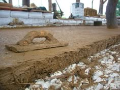 a pile of dirt sitting on top of a dirty ground next to trees and piles of hay