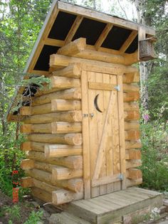 a small wooden cabin in the woods with a door and window on it's side