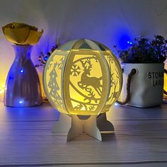 an illuminated lamp sitting on top of a wooden table next to vases and flowers