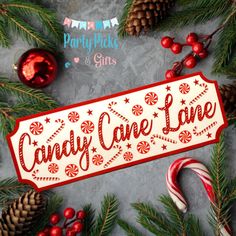 a candy cane lane sign sitting on top of a table next to pine cones and christmas decorations